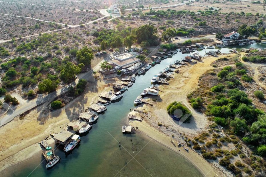Aerial bird's eye view of Liopetri river to the sea (potamos Liopetriou), Famagusta, Cyprus. A landmark tourist attraction fishing village, natural fjord with colourful boats moored on the banks at Kokkinochoria, Ammochostos, from above.
